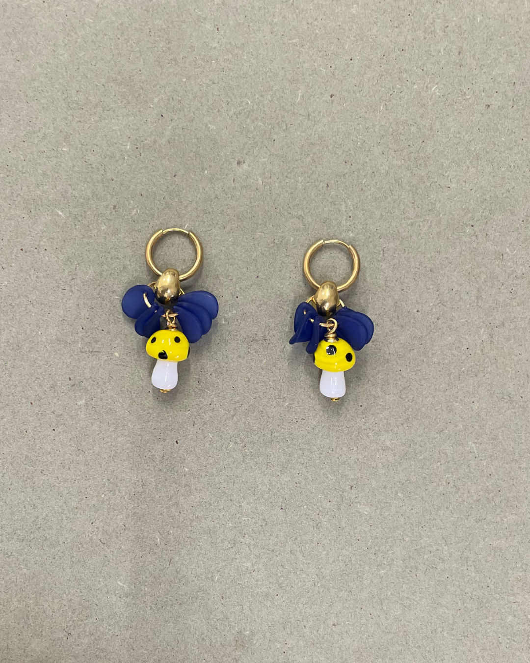 Argolas Mushrooms de aço com cogumelos de vidro, com cogumelo amarelo, em fundo cinzento