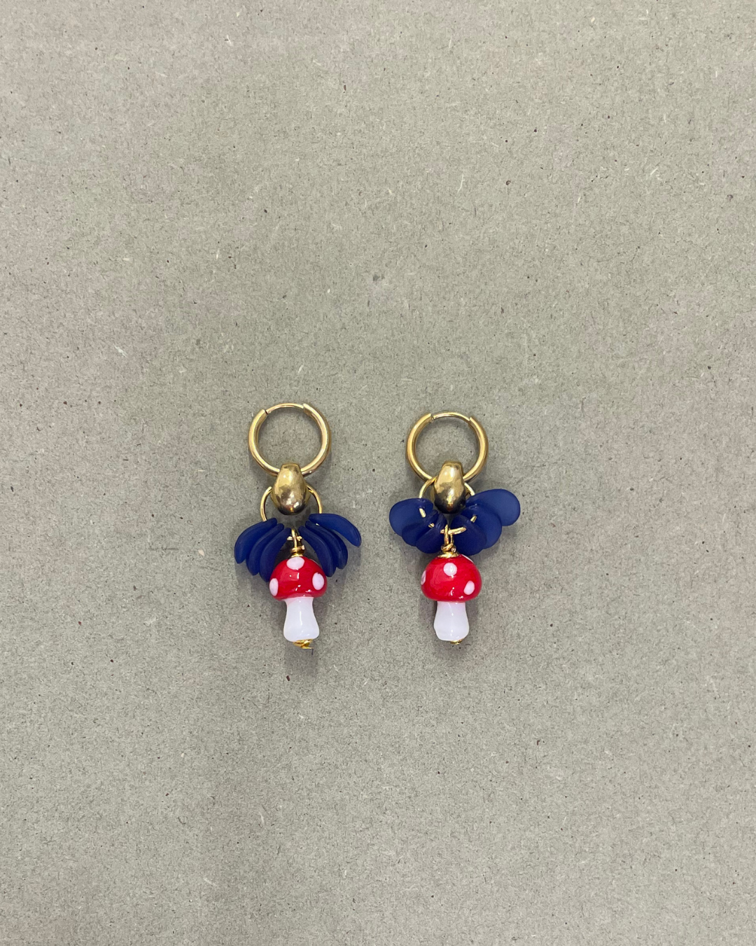 Argolas Mushrooms de aço com cogumelos de vidro, com cogumelo vermelho, em fundo cinzento