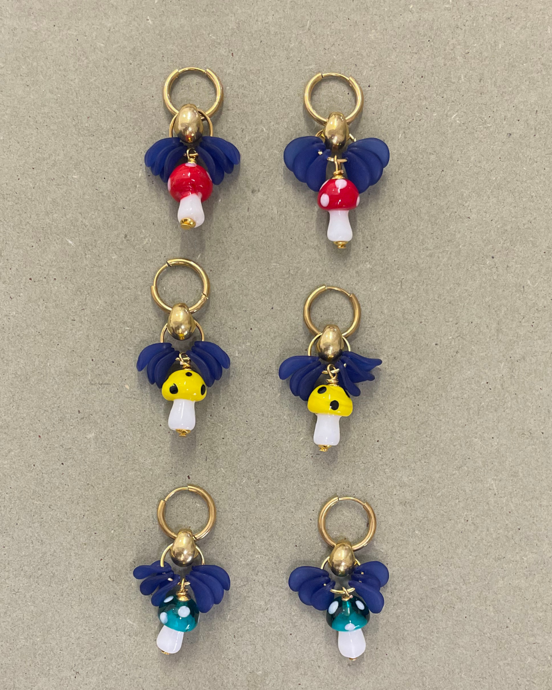 Argolas Mushrooms de aço com cogumelos de vidro, três cores lado a lado, em fundo cinzento