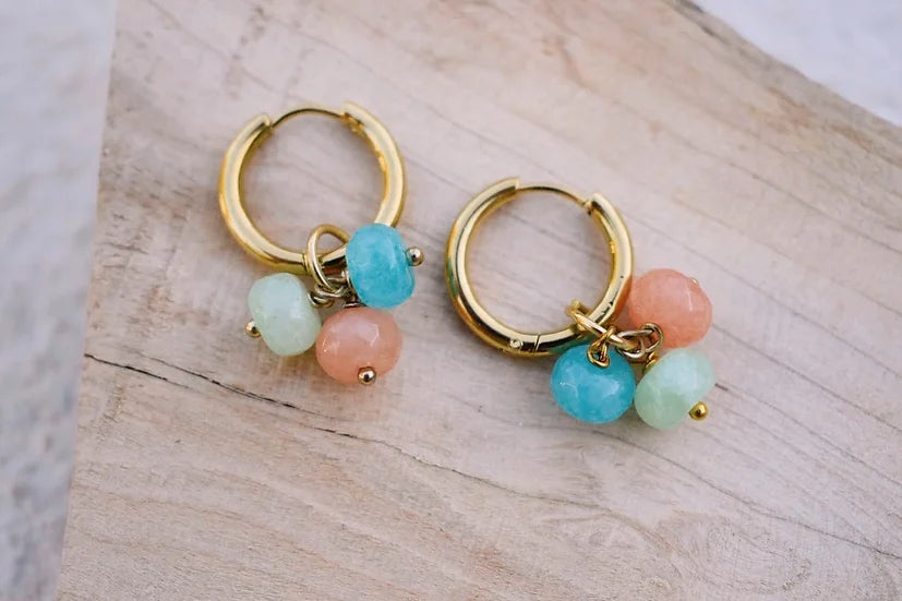 Argolas Treviso de aço com jade facetado, com jade turquesa e coral, sobre madeira