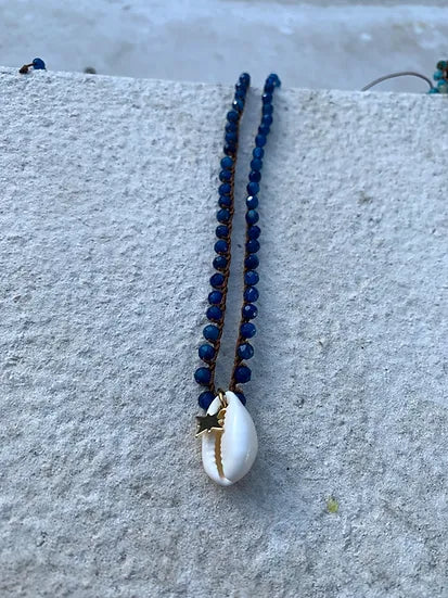 Colar Bacio di Mare de ágatas com concha, azul, sobre pedra junto à piscina