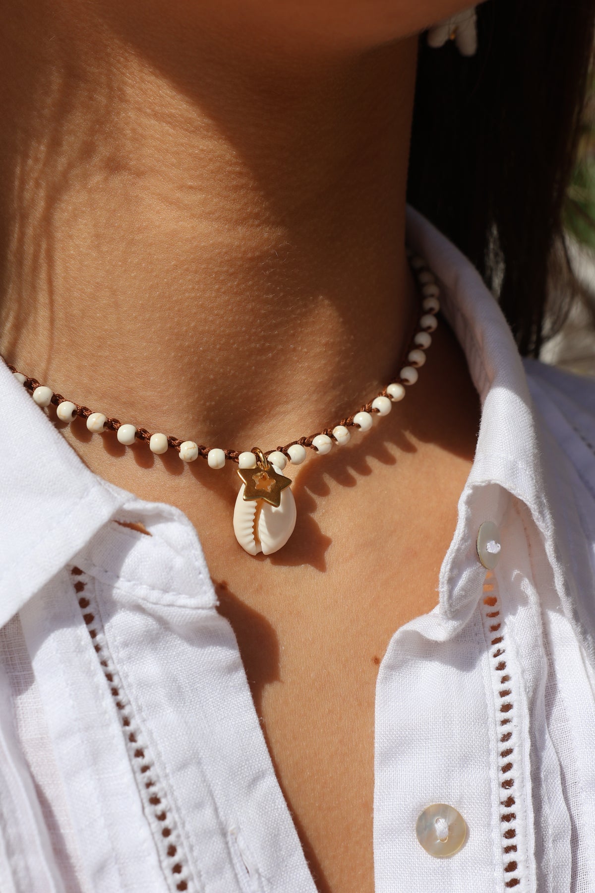 Colar Bacio di Mare de ágatas com concha, usado por modelo com camisa branca