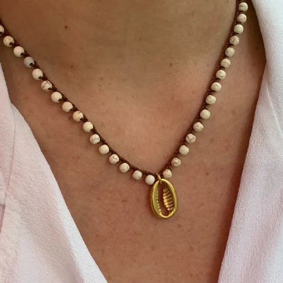 Colar Bacio di Mare de howlite com concha, com concha dourada, usado ao pescoço