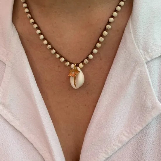 Colar Bacio di Mare de howlite com concha, usado ao pescoço com camisa rosa