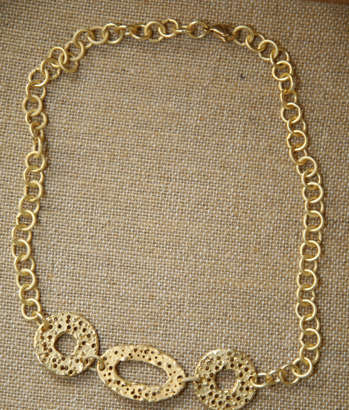 Colar Choker de corrente dourada, com elos ovais, sobre tecido de linho
