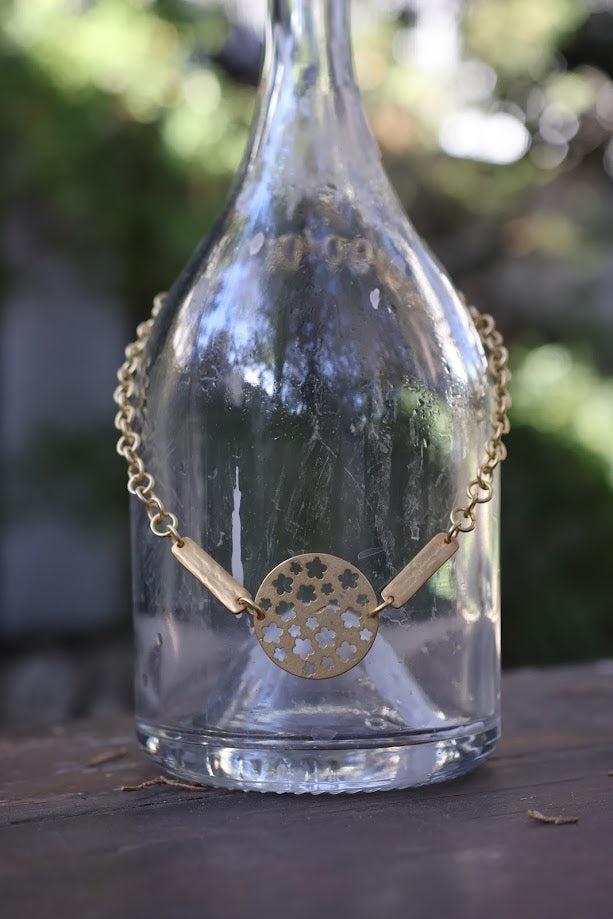 Colar Choker de corrente dourada, pendurado numa garrafa de vidro, de perto