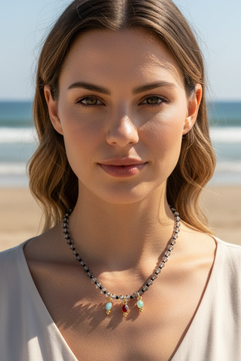 Colar com pendentes verde e vermelho numa modelo ao pé do mar