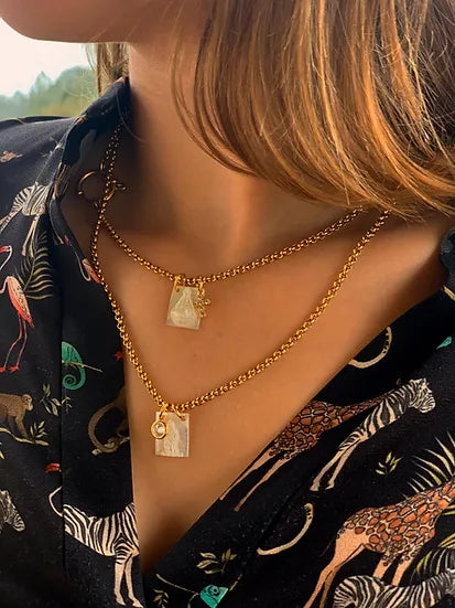 Colar escapulário duplo C&P de aço e madrepérola, usado com blusa estampada
