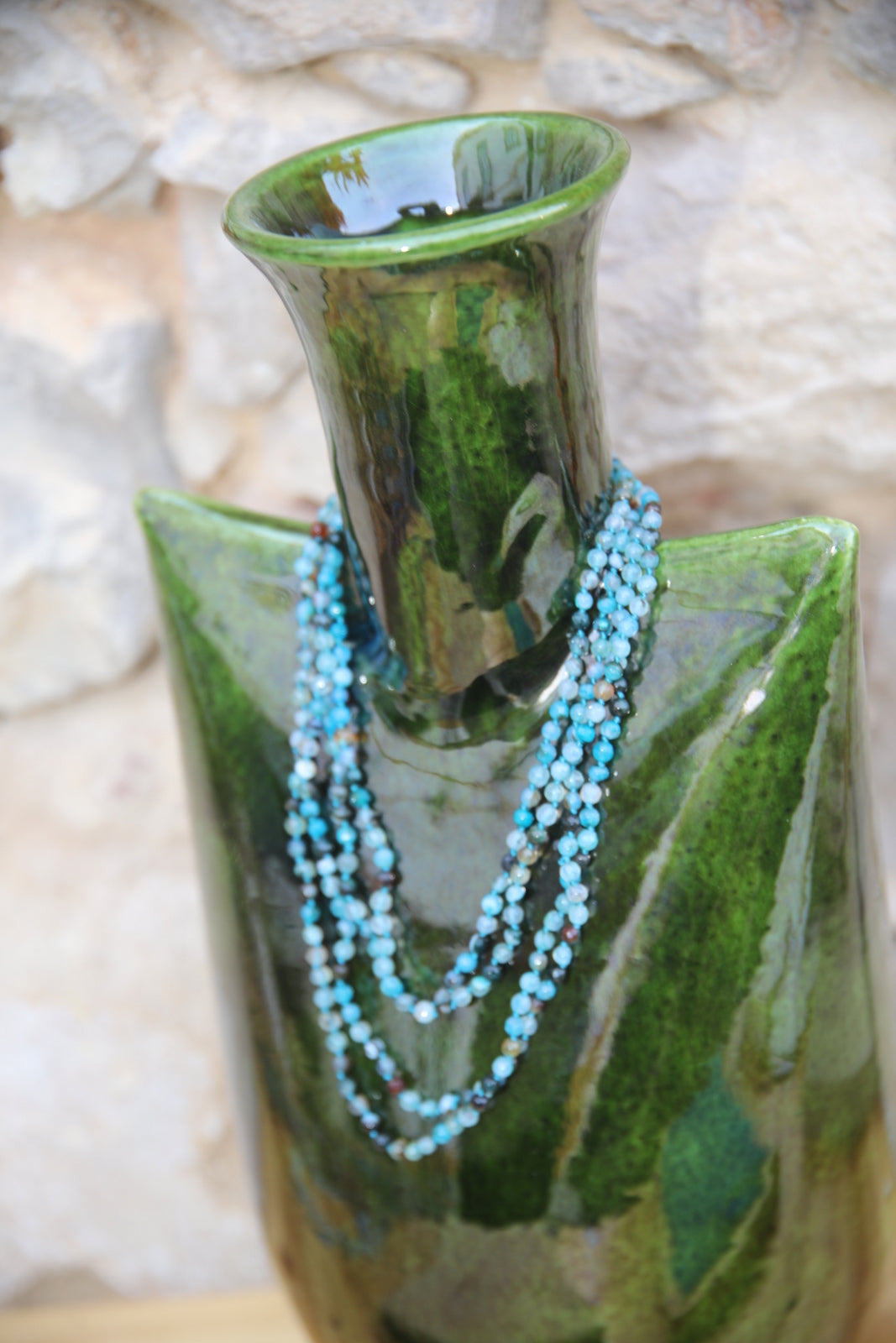 Colar Infinity de ágatas em fio de seda, azul, enrolado numa jarra de vidro verde