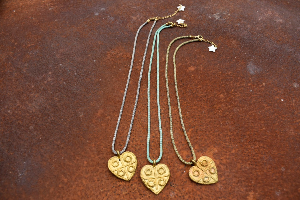Colar Milano I de malha metálica com coração de bronze, três cores com pendente de coração, sobre fundo cor de ferrugem
