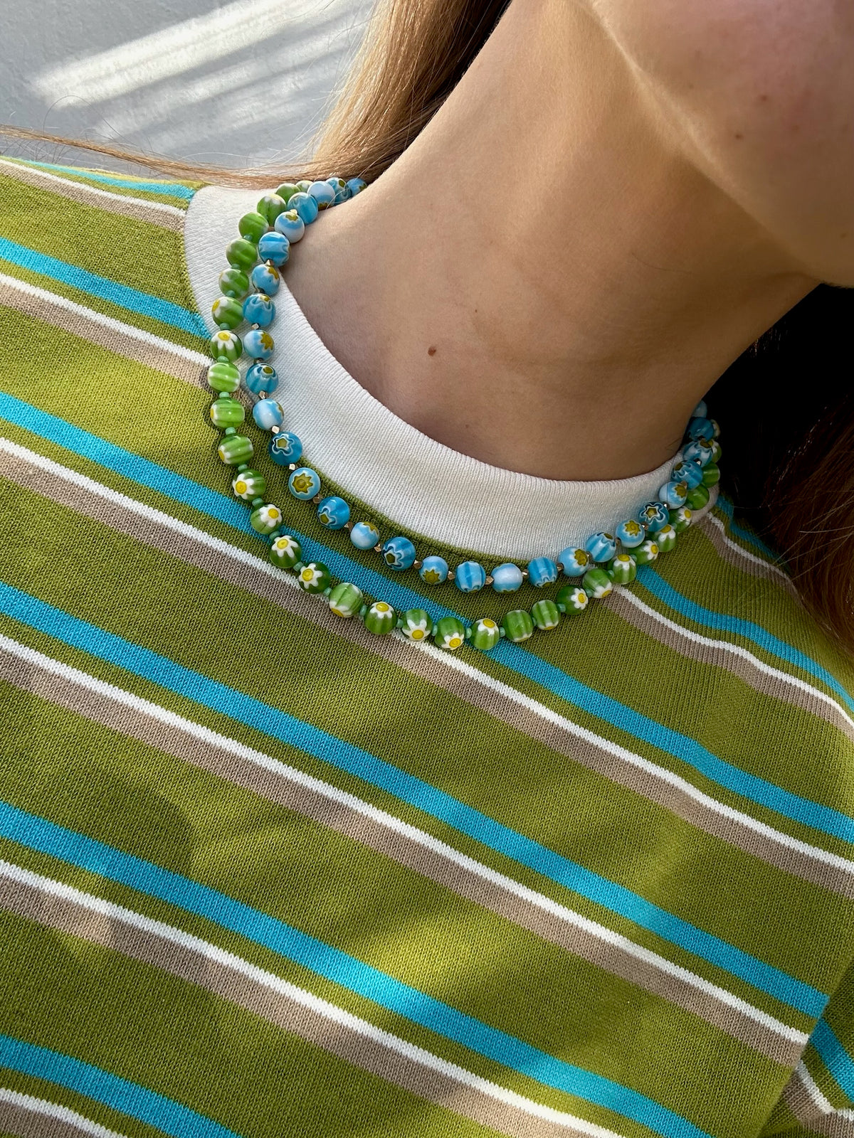 Colar Millefiori de vidro, usado ao pescoço com camisola às riscas