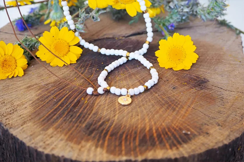 Colar Mónica de howlite com medalha, sobre madeira, com flores amarelas