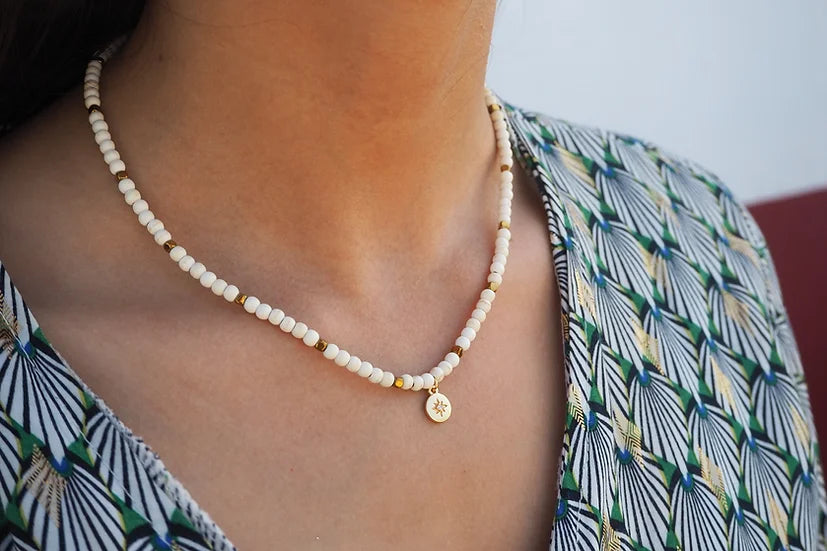 Colar Mónica de howlite com medalha, usado ao pescoço com blusa estampada