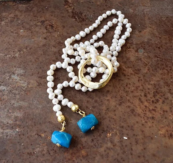 Colar Nina de pérolas com ágata azul, com terminais azuis, sobre fundo cor de ferrugem