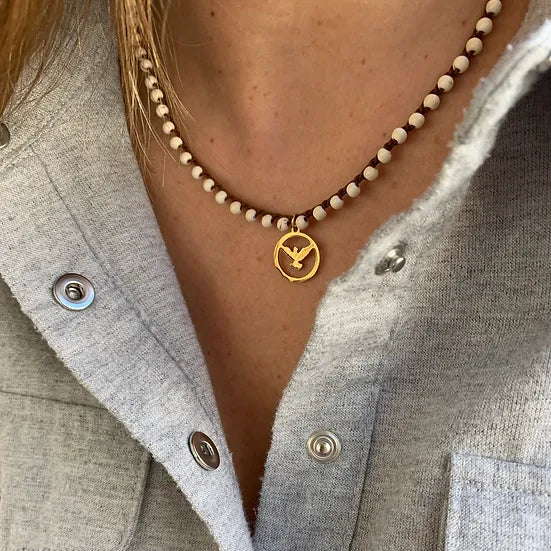 Colar Sofia de howlite, com medalha, usado com camisa cinzenta