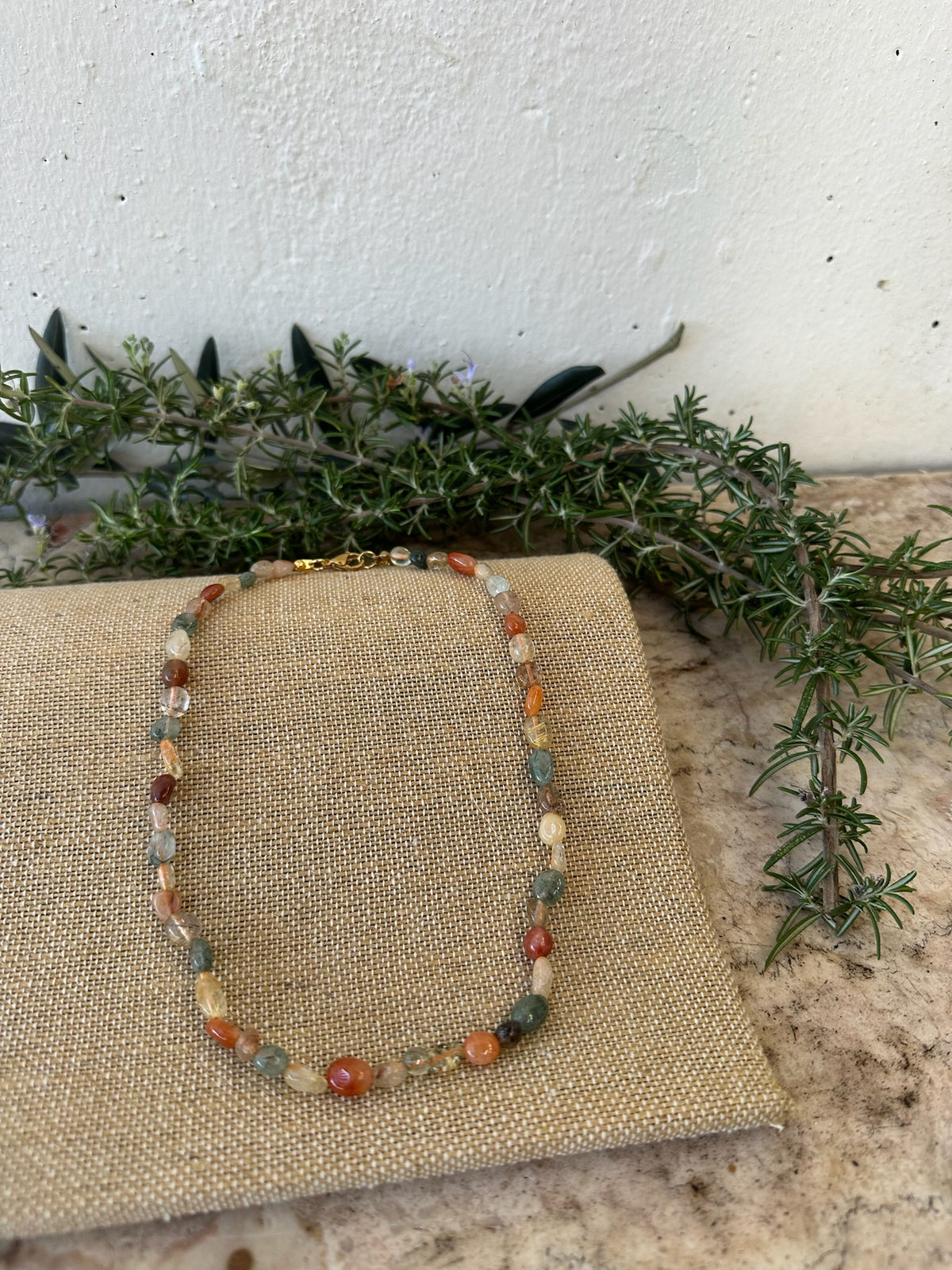 Colar Stone de amazonite, tons de tijolo, sobre linho com ramos verdes