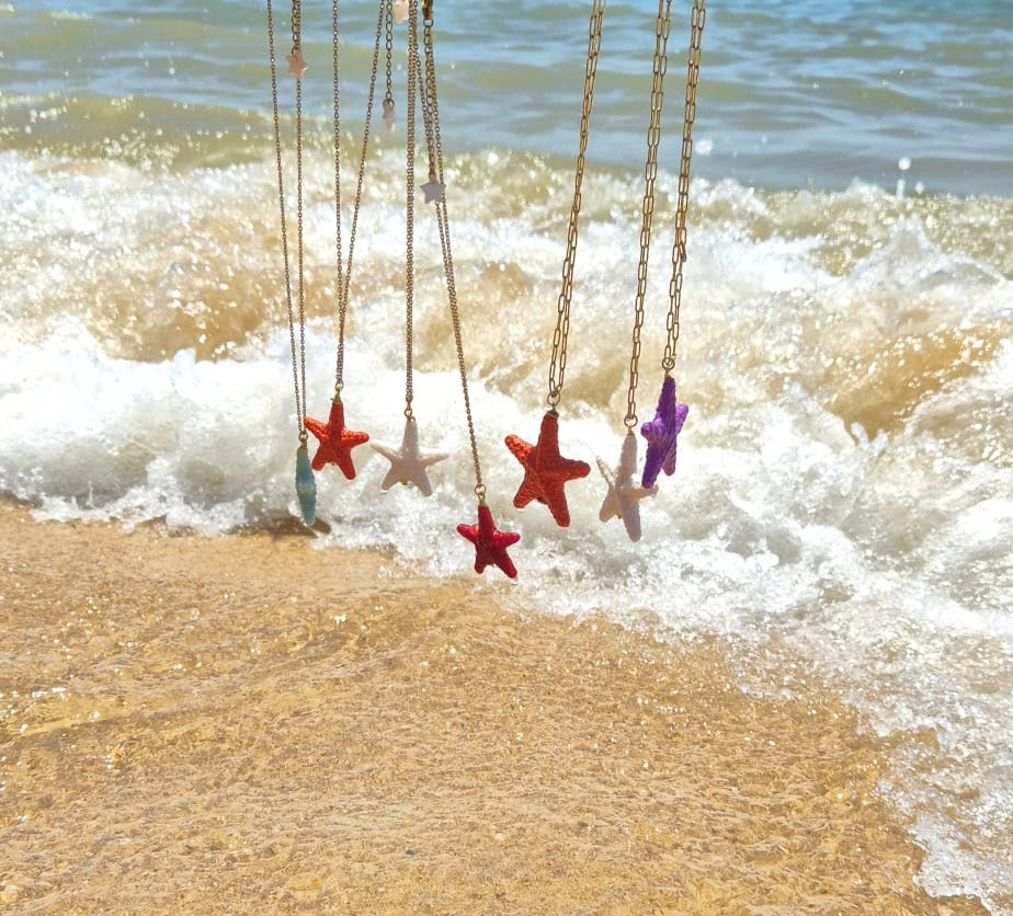 Colar Summer Star de aço com estrela de resina, vários colares na areia, junto ao mar