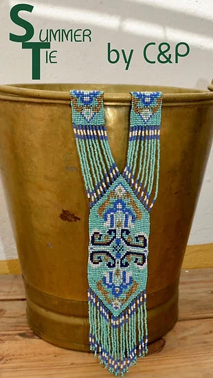 Colar Tie de missangas, num vaso dourado, com etiqueta da marca